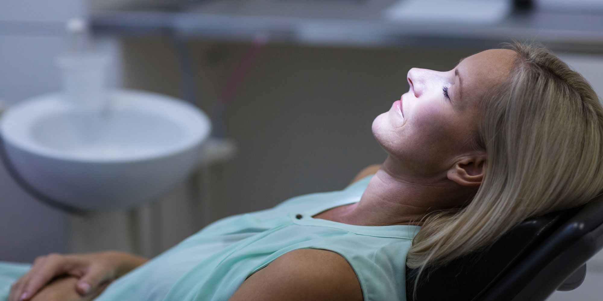 A patient resting with her eyes closed in the chair under sedation