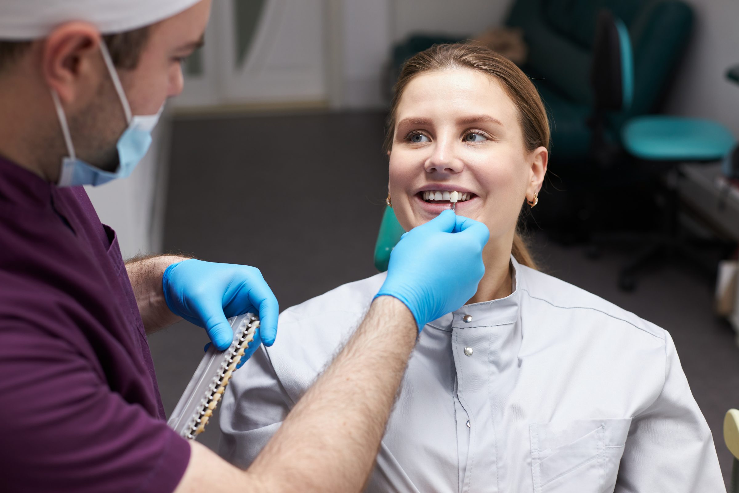 A clinician compares a shade guide with a patient's teeth