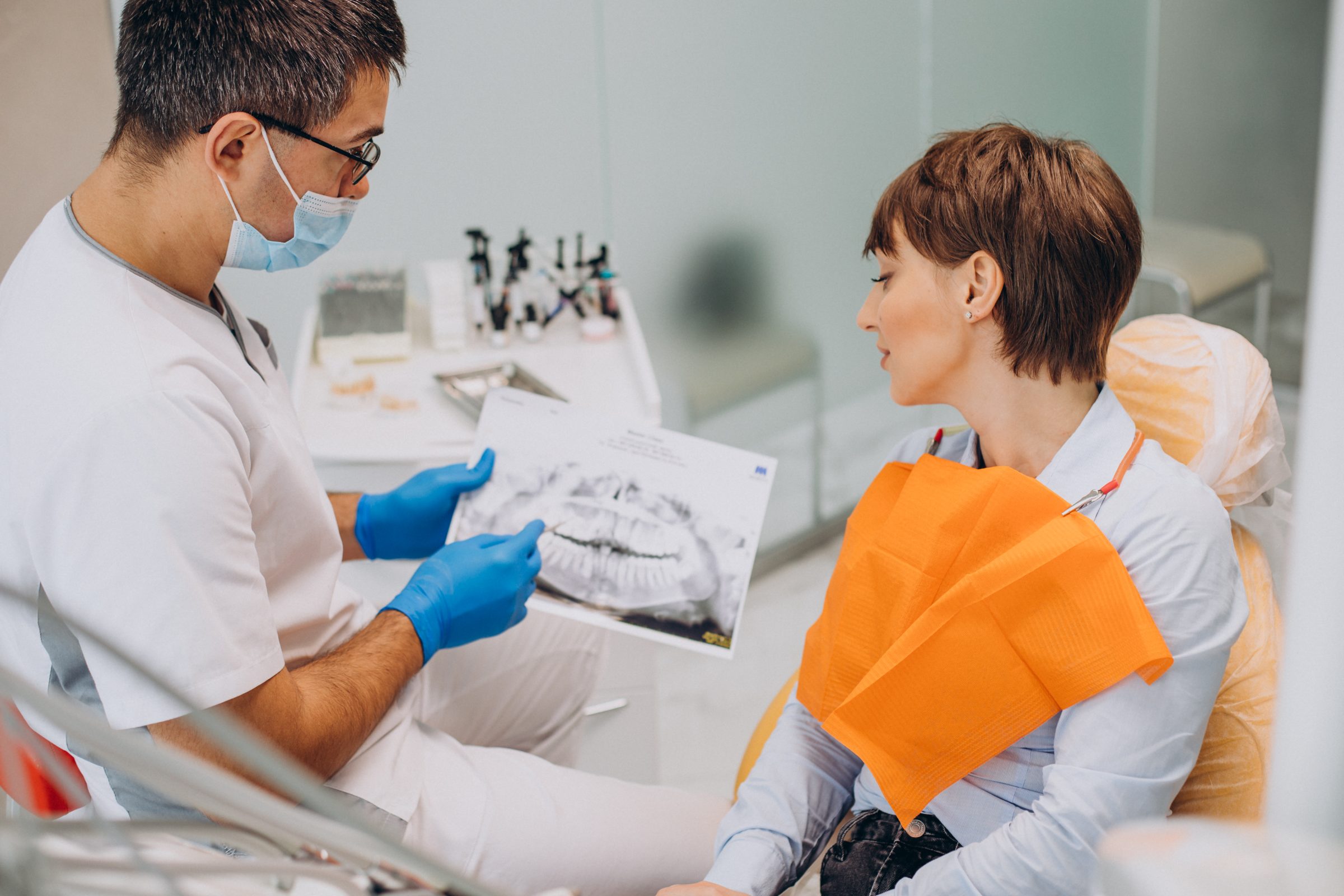 A dentist goes over a printed scan of the teeth with a patient in the dental chair