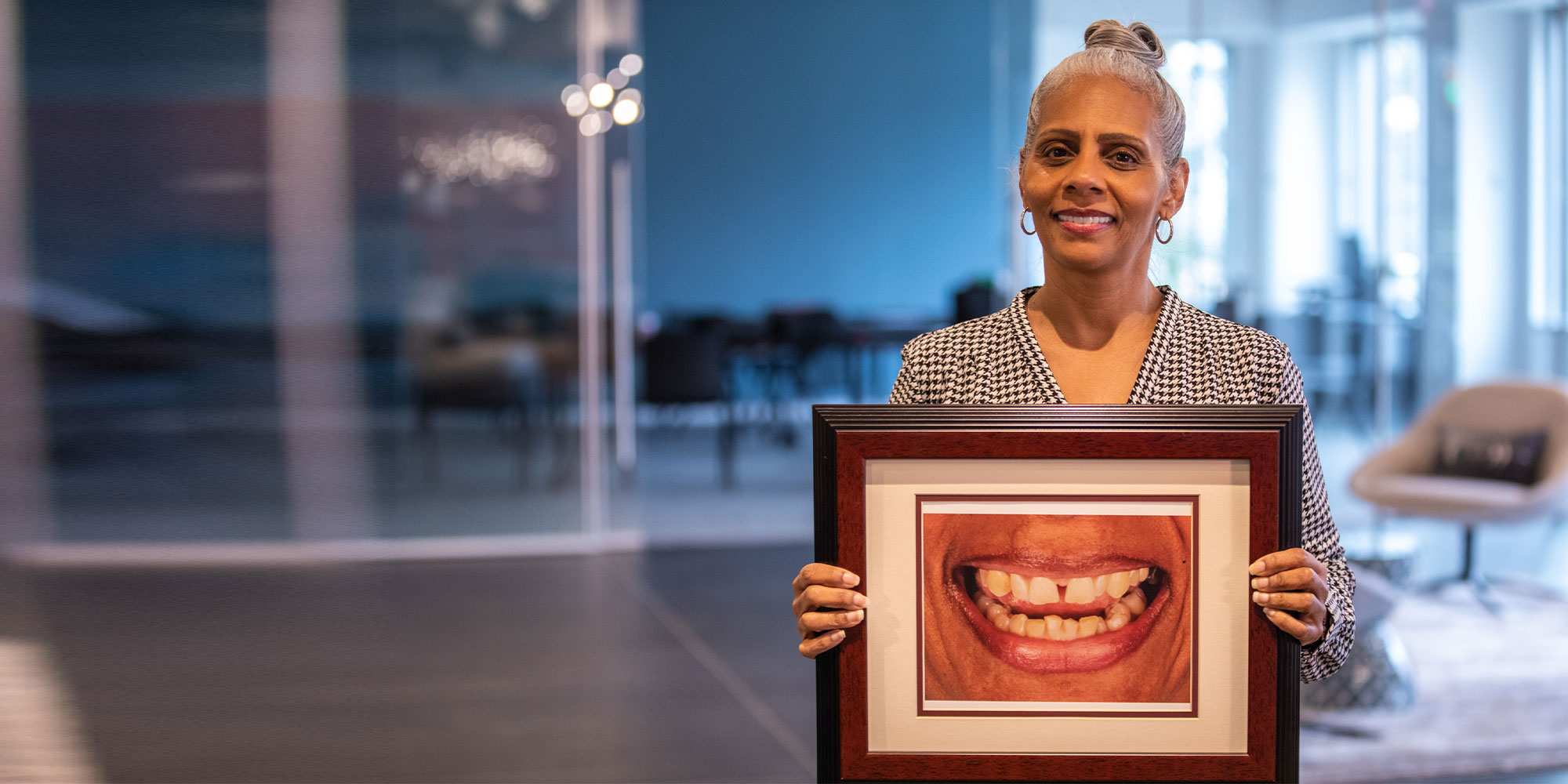 Yolanda holding a framed photograph of her smile before treatment
