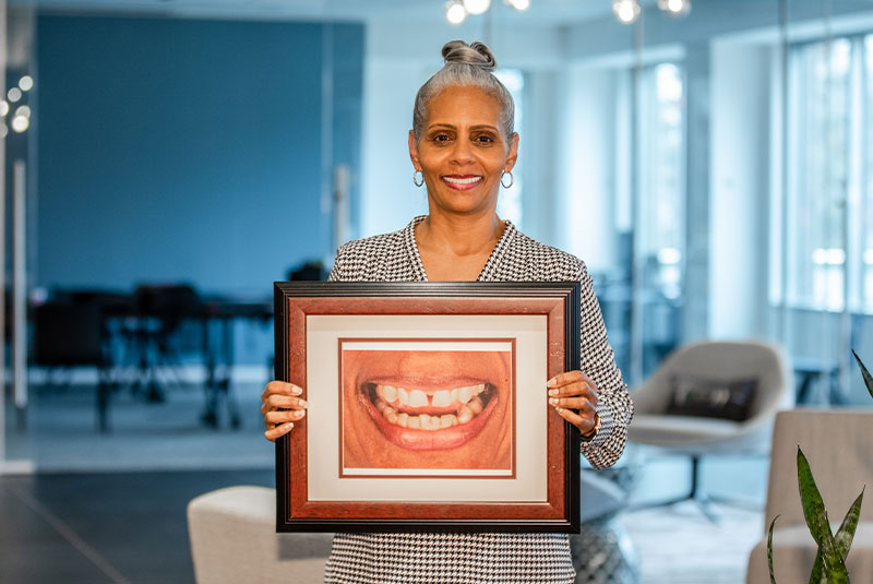 Yolanda holding a framed photograph of her smile before treatment