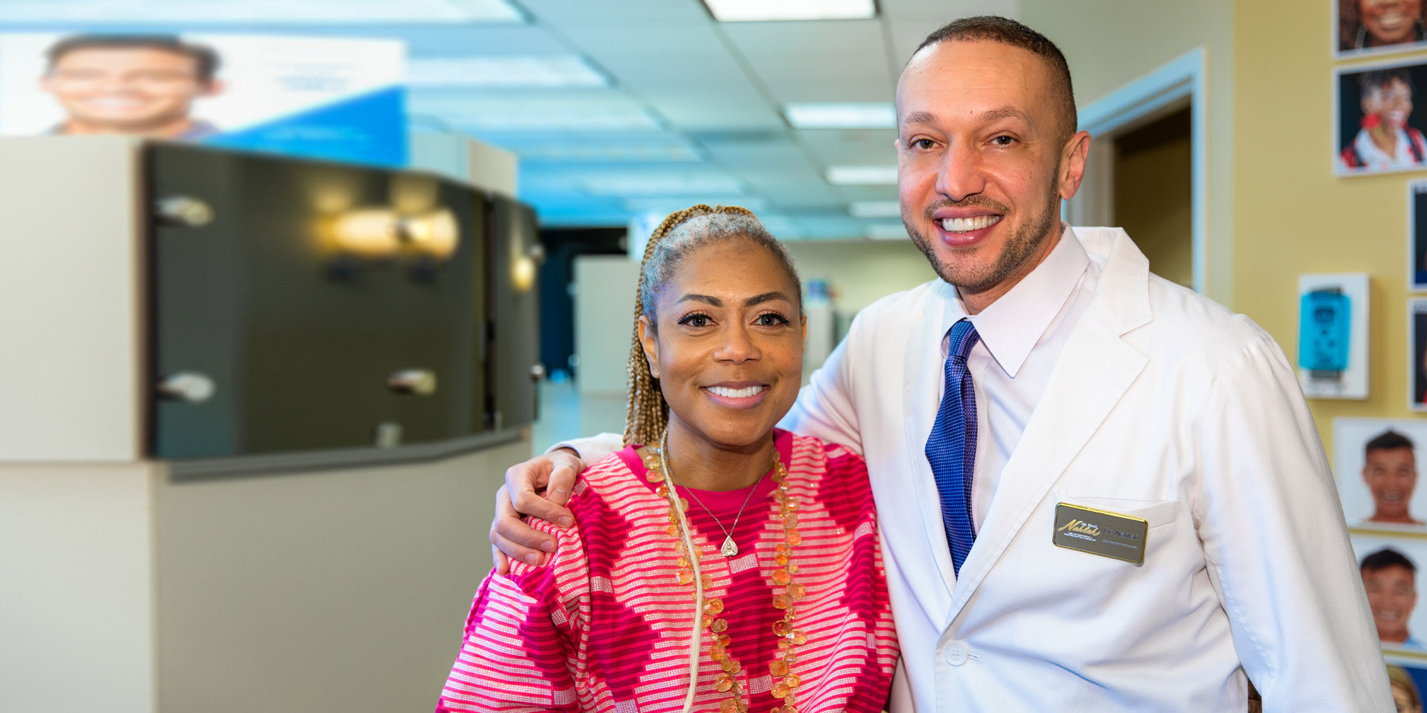Dr. Nahlah standing with a smiling patient in the practice corridor