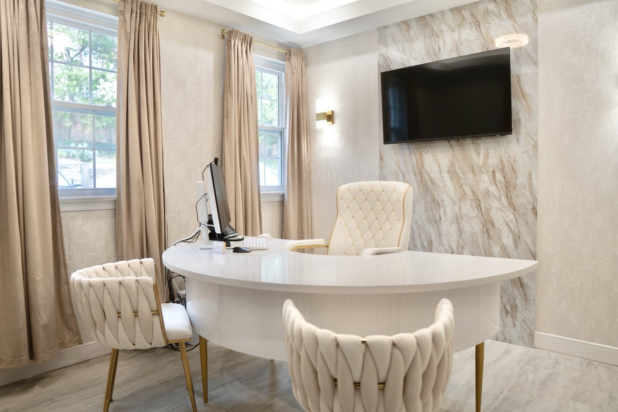 A consultation room at the Alexandria office, with a white desk, upholstered chairs and a marble feature wall