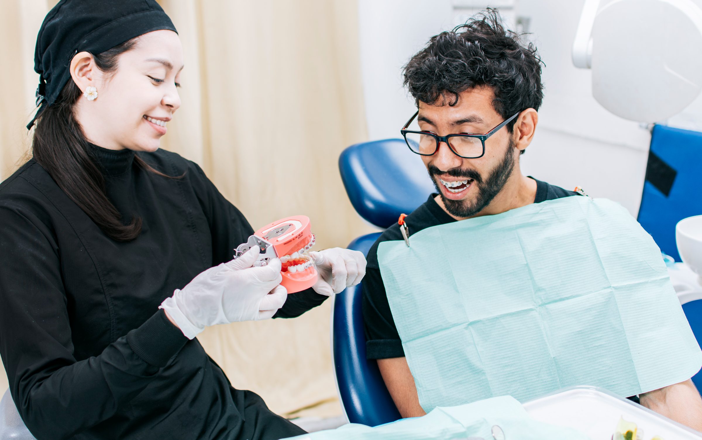 A clinician shows a smiling patient in the dental chair a model of the teeth